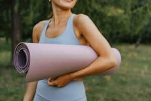 A woman golding a yoga mat under her arm